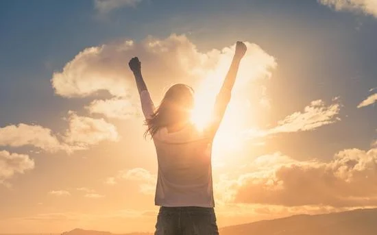 Person, die im Sonnenlicht die Arme hebt